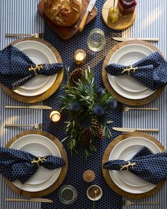 the table is set with pineapples, blue napkins and gold place settings