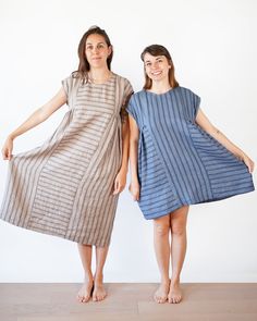 two women standing next to each other wearing dresses with stripes on the front and back