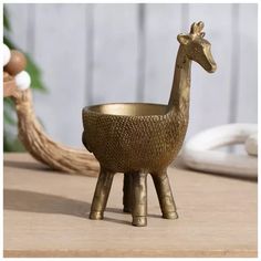 a small brass giraffe sitting on top of a wooden table