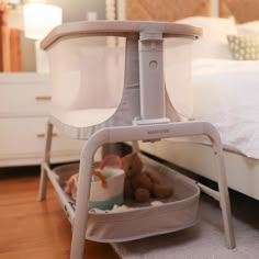 a baby crib with a teddy bear in it on the floor next to a bed