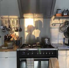 a couple kissing in the kitchen next to an oven with pots and pans on it