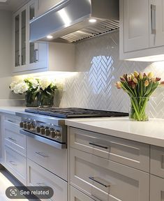 a kitchen with white cabinets and flowers in vases on the stove top burner