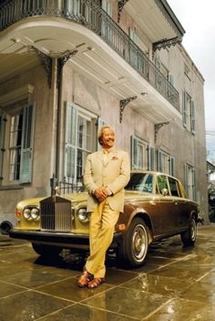 a man sitting on the hood of a car in front of a building with balconies