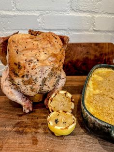 a chicken sitting on top of a wooden cutting board next to an egg and some other food