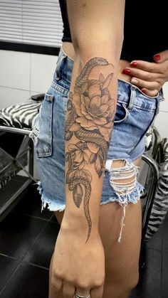 a woman with a flower tattoo on her arm and leg is standing in front of a mirror