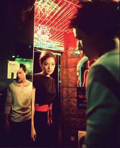 a woman standing in front of a mirror next to a man wearing a green shirt