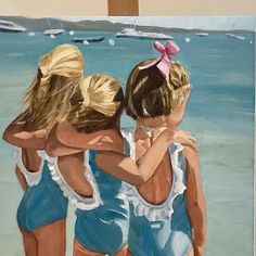 three girls hugging on the beach in front of an easel with water behind them