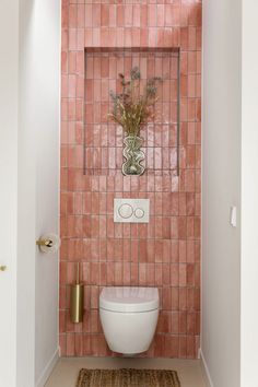 a white toilet sitting in a bathroom next to a pink tiled wall and gold accents