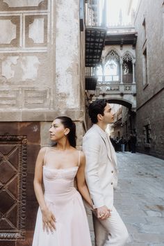 a man and woman standing next to each other in front of a building on the street