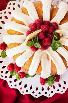 a cake with white frosting and strawberries on top sitting on a doily