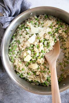 a pot filled with rice and peas on top of a table next to a wooden spoon