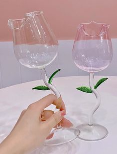 two wine glasses that are sitting on a table, one is pink and the other is white