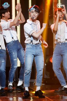 group of young men performing on stage with their hands in the air