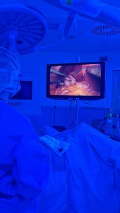 two surgeons in scrubs watching television with neon blue lighting on the wall behind them