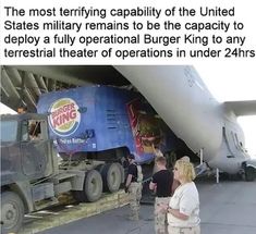 two people standing in front of a large truck under an airplane that is being unloaded