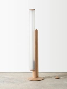 a lamp that is on top of a wooden stand next to a white wall and floor