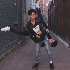 two young men are dancing in the alley way with one holding on to his leg