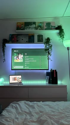 a bed with a laptop on top of it in front of a flat screen tv