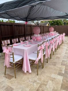 a table set up for a baby shower with pink and white decorations on the tables