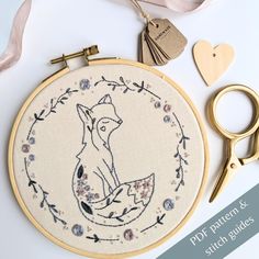 an embroidery kit with scissors and other crafting supplies on it, including a fox