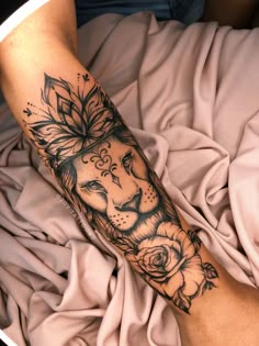 a man's arm with a lion and roses tattoo on the left side of his arm