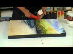 a person is using a brush to paint a painting on a board with acrylic paints