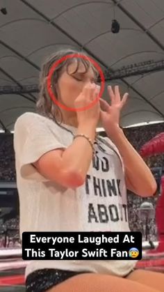 a woman standing in front of a crowd with her hand up to her mouth and the words everyone laughing at this taylor swift fan