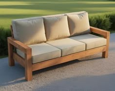 a wooden couch sitting on top of a gravel road next to a lush green field