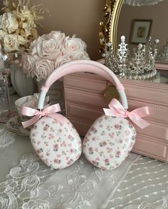 two pink and white flowered purses with bows on them sitting next to a mirror