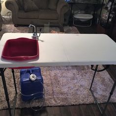 a white table with a red sink on it in front of a couch and chair