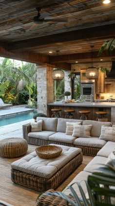 an outdoor living area with couches and tables next to a swimming pool in the background