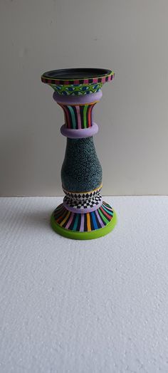 a colorful vase sitting on top of a white table next to a black and green object