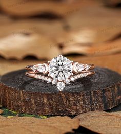 an engagement ring on top of a piece of wood with leaves in the back ground