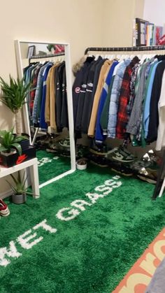 a room filled with lots of clothes on hangers next to a green carpeted floor