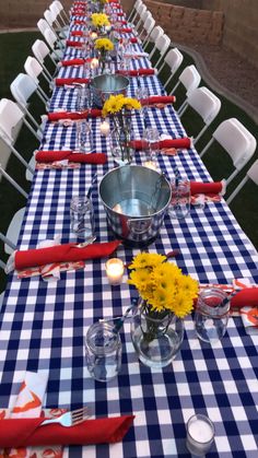 a long table with blue and white gingham cloth, yellow flowers in vases