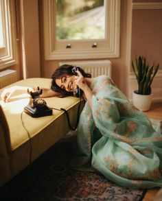 a woman sitting on a couch talking on a phone