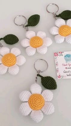 four crocheted key chains with white and yellow flowers attached to each one's sides