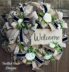 a welcome wreath hanging on the side of a wooden door with flowers and ribbon around it