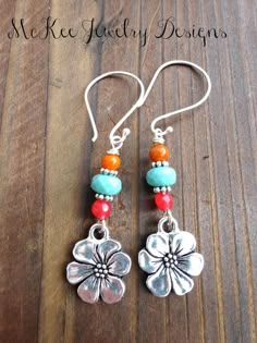 the earrings are made with silver and turquoise beads, coral beaded accents, and flower charms