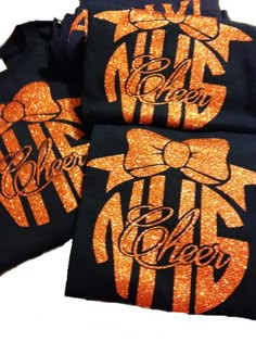 two black shirts with orange letters on the front and back, one has an orange bow