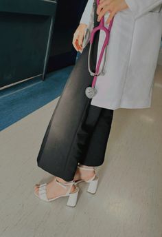 a woman in white lab coat holding a black bag with a pink stethoscope on it