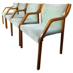 three chairs with wooden arms and green upholstered seats