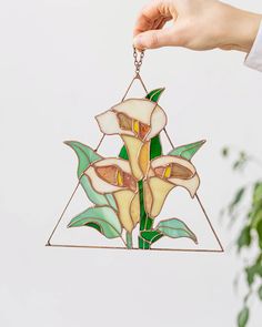 a hand holding a stained glass hanging ornament with flowers