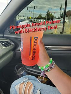 a person holding a drink in their hand while sitting in a car with the text pineapple almond palmer with blackberry float