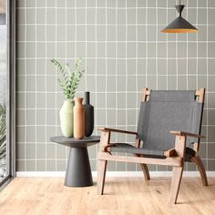 a chair and table with vases on it in front of a wallpapered room