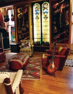 a living room filled with lots of furniture and guitars hanging from the wall next to each other