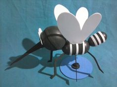 a paper sculpture of a bee on a blue surface