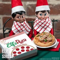 two elfs sitting at a table with pizza and pizza box