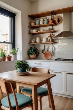 a kitchen with wooden table and chairs next to open shelves filled with potted plants