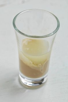 a glass filled with liquid sitting on top of a table